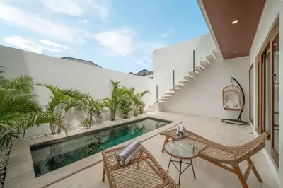 an outdoor patio with a swimming pool and chairs at Cute 2 Bedrooms Villa in Canggu in Canggu