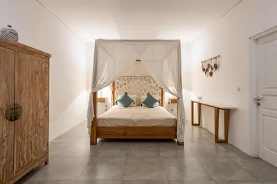 a bedroom with a canopy bed with blue pillows at Central Oberoi Seminyak Newly Renovated Villa Riva in Seminyak