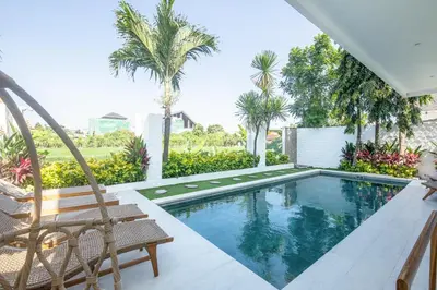 a swimming pool with two chairs and palm trees at 4 Bd Seminyak Scenic Rice Views 4 mins to Beach in Seminyak