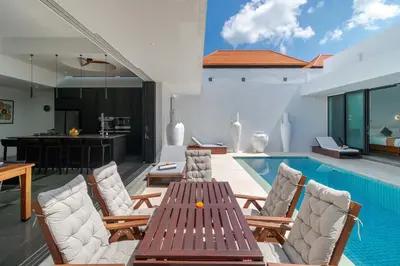 a pool with a table and chairs next to a swimming pool at Stylish 3BR Villa with Swim-Up Bar in Seminyak in Seminyak