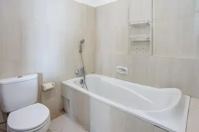 a bathroom with a toilet and a bath tub with a toilet at Prima Inn in Kuta