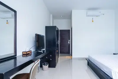 a bedroom with a desk with a television and a bed at Prima Inn in Kuta
