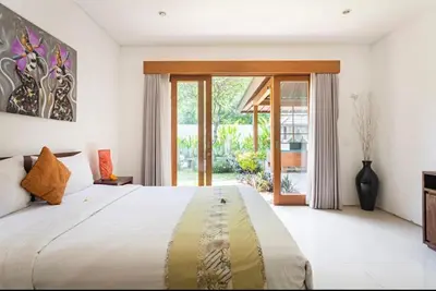 a bedroom with a large bed and a large window at Bunga Neil Villa in Seminyak