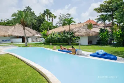 a pool at a resort with two people sitting on inflatables at The Apartments Umalas in Canggu