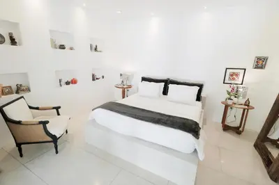 a white bedroom with a large bed and a chair at The Apartments Umalas in Canggu
