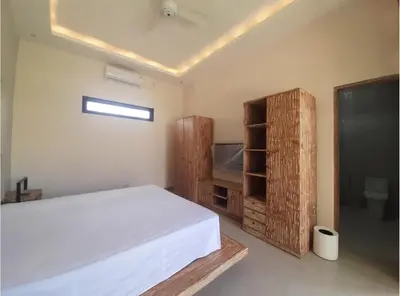 a bedroom with a white bed and a television at Villa Rova in Kerobokan