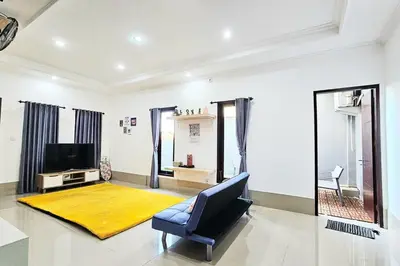 a living room with a blue chair and a yellow rug at 4 Bedroom Home with Pool near Canggu and Seminyak in Kerobokan