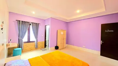 a bedroom with purple walls and a bed with a yellow blanket at 4 Bedroom Home with Pool near Canggu and Seminyak in Kerobokan
