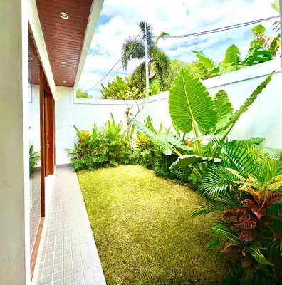 a garden with green plants on the side of a house at Mahayasa Villa with garden in Canggu