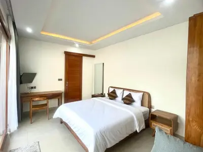 a bedroom with a white bed and a desk at Mahayasa Villa with garden in Canggu