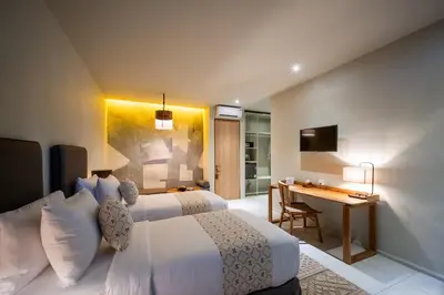 a hotel room with two beds and a desk at Anam Tang New Rooms & Cafe near Seminyak in Seminyak