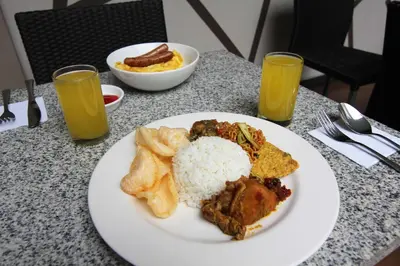 a plate of food with rice and other foods on a table at Choice Stay Hotel Denpasar in Denpasar