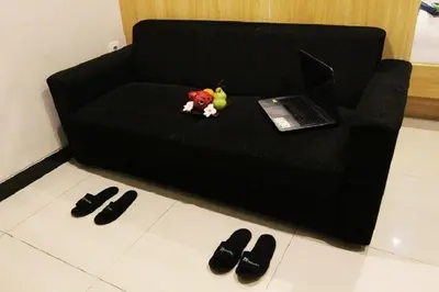 a black couch with a laptop and a pile of shoes at Choice Stay Hotel Denpasar in Denpasar