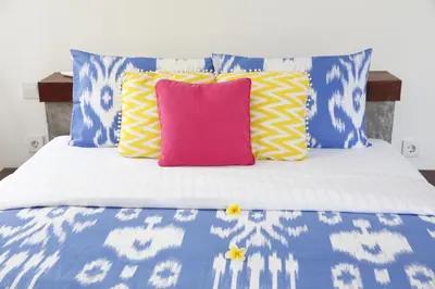 a bed with blue and white pillows and a pink pillow at Villa Turtle in Seminyak