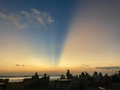 a group of people sitting on the beach watching the sunset at Bali Bliss Jayakarta Apartments in Seminyak