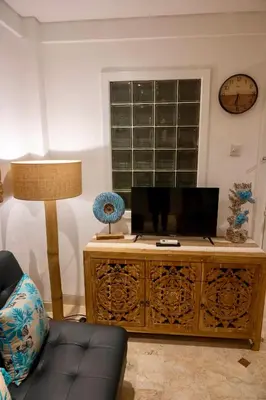 a living room with a wooden cabinet and a clock at Bali Bliss Jayakarta Apartments in Seminyak
