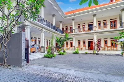 a large white building with a courtyard at Collection O Budget Door Legian Inn @Poppies Road in Legian