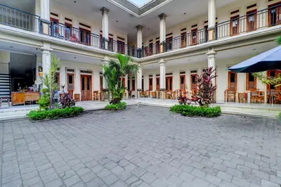a courtyard of a building with palm trees in it at Collection O Budget Door Legian Inn @Poppies Road in Legian