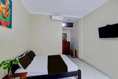 a bedroom with a bed and a tv on a wall at Collection O Budget Door Legian Inn @Poppies Road in Legian