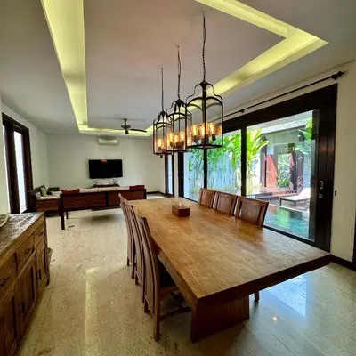 a dining room with a large wooden table and chairs at Tolgay Living Villas in Seminyak