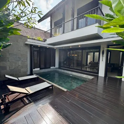 a swimming pool in front of a house at Tolgay Living Villas in Seminyak