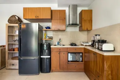 a kitchen with wooden cabinets and a stainless steel refrigerator at Tolgay Living Villas in Seminyak