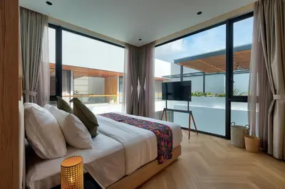a bedroom with a large bed and a balcony at Villa Brandon by Nakula in Jimbaran