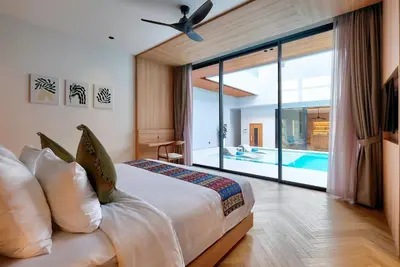 a bedroom with a bed with a view of a pool at Villa Brandon by Nakula in Jimbaran