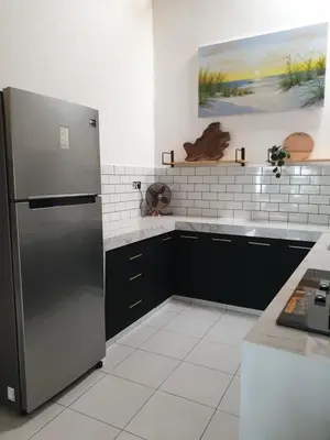 a kitchen with a stainless steel refrigerator and black cabinets at Vina villa in Kerobokan