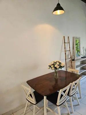 a dining room table with chairs and a vase of flowers at Vina villa in Kerobokan