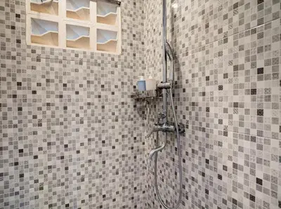 a shower in a bathroom with a tiled wall at Aspen bali nusa dua in Nusa Dua