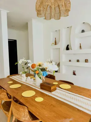 a dining room with a wooden table with flowers on it at Casa Yo-Na Seminyak in Seminyak