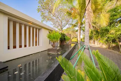 a house with a swimming pool and palm trees at Villa Ramadewa Beachside with Authentic Charm in Seminyak