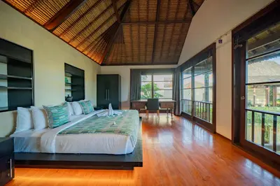 a bedroom with a bed in a room with windows at Villa Ramadewa Beachside with Authentic Charm in Seminyak