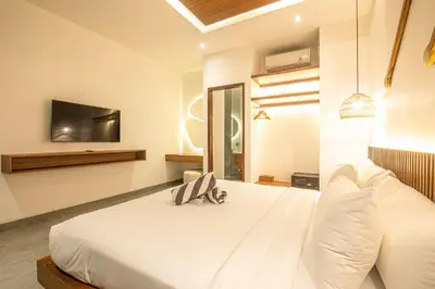 a bedroom with a white bed with a tv on the wall at Tropical 5BR Modern Haven 400m from Canggu in Canggu