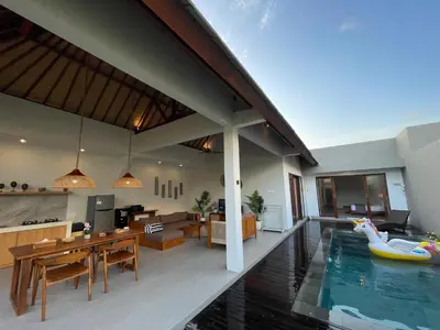 a house with a swimming pool and a living room at Villa Sinergi Seminyak 8 in Seminyak