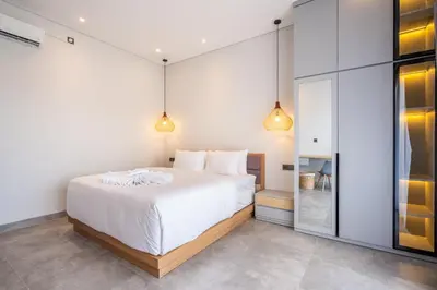 a bedroom with a large white bed and two lights at Villa Baile Bali by Great Bali Villas in Jimbaran