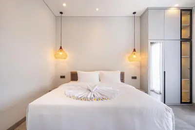 a bedroom with a white bed with two lights at Villa Baile Bali by Great Bali Villas in Jimbaran