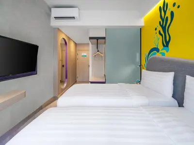 a hotel room with two beds and a tv at Quest Vibe Dewi Sri Bali in Legian
