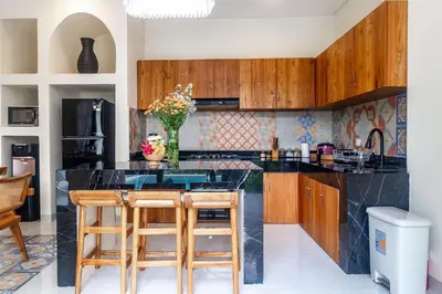 a kitchen with a black counter and wooden cabinets at Villa Amaia Bali in Kerobokan