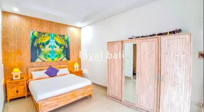 a bedroom with a bed and a painting on the wall at Villa GOwen in Jimbaran