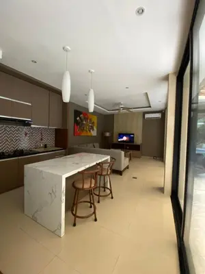 a kitchen with a large white counter and chairs at Vila Samatha 2 Nusa Dua in Nusa Dua