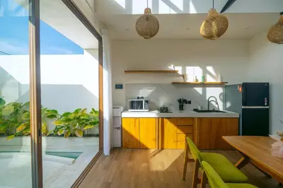 a kitchen with wooden cabinets and a table with green chairs at NEW! Villa Imaera - 2BR Villa in Kerobokan in Kerobokan