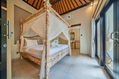 a bedroom with a canopy bed in a room at Villa Cahaya Berlian in Kerobokan