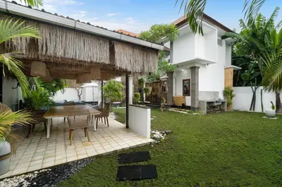 a patio with a table and chairs in a yard at Villa Zambrud Sanur Elegant Tropical Villa with Private Pool & Garden and Garage in Sanur