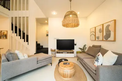 a living room with two couches and a television at Villa Zambrud Sanur Elegant Tropical Villa with Private Pool & Garden and Garage in Sanur