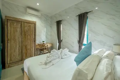 a bedroom with a white bed and a desk at Beachview Residence in Seminyak