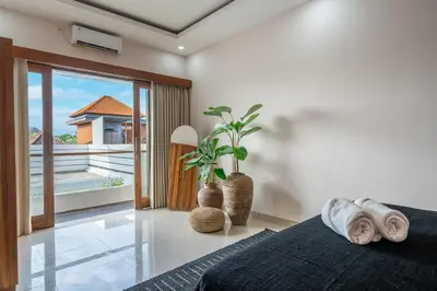 a bedroom with a bed and a view of a balcony at Kutesa Villa - Cozy Villa with Dreamy Swim Spot in Kerobokan