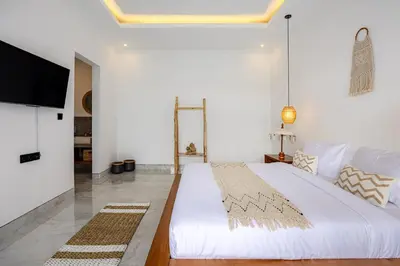 a white bedroom with a large bed and a flat screen tv at Brand New Serene Balinese Villa with Private Pool in Kerobokan