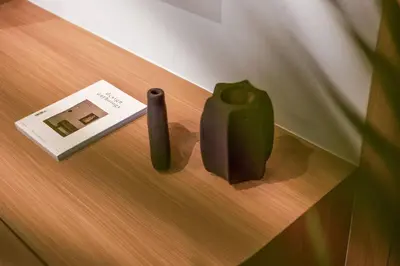 a green vase and a book on a table at New 2BR Architectural Masterpiece in Umalas in Kerobokan